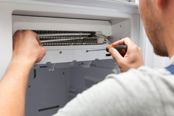 The repairer is fixing the freezer at home